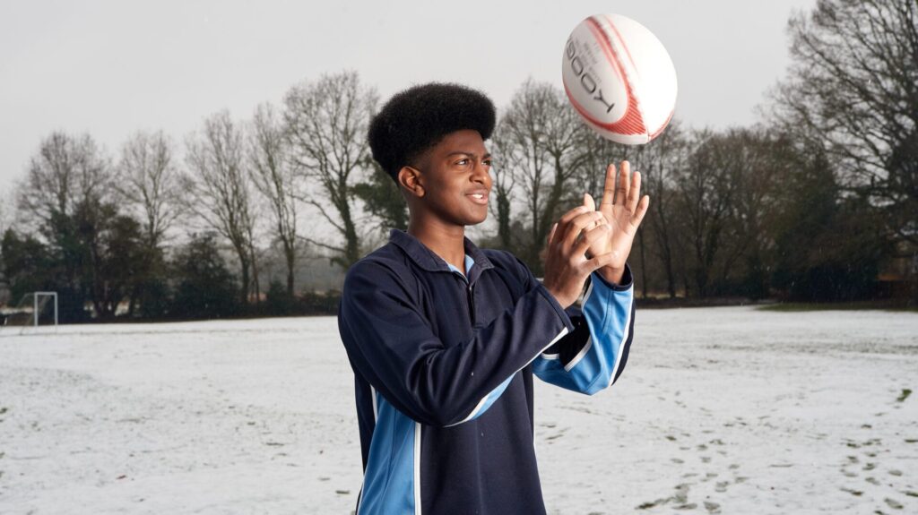 boy lifting up a rugby ball into the air