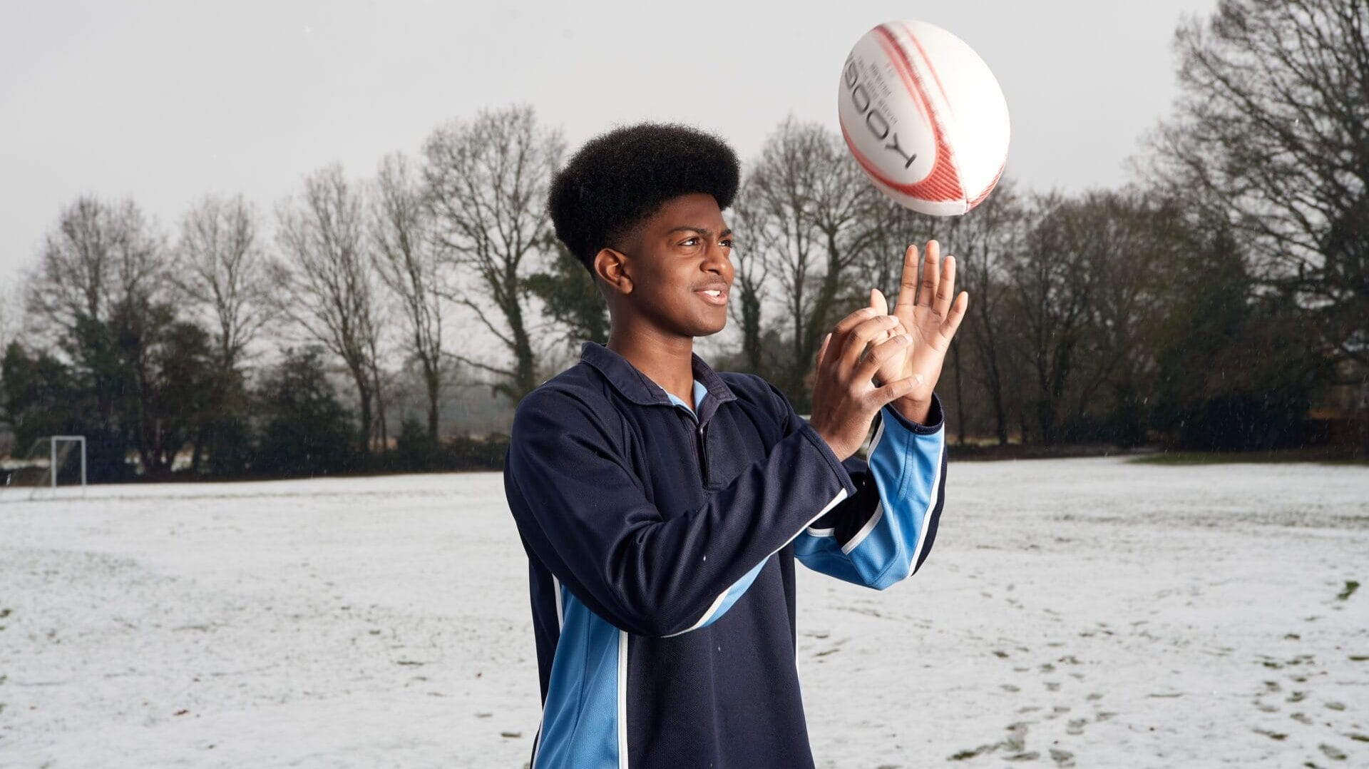 boy lifting up a rugby ball into the air